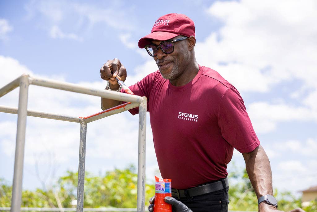 Leading by example, during the official launch of the Sygnus Foundation, president and CEO of Sygnus Capital Berisford Grey helps kick off playground improvement activities at Barbary Hall Primary and Infant School by adding a fresh coat of paint to the monkey bars.x